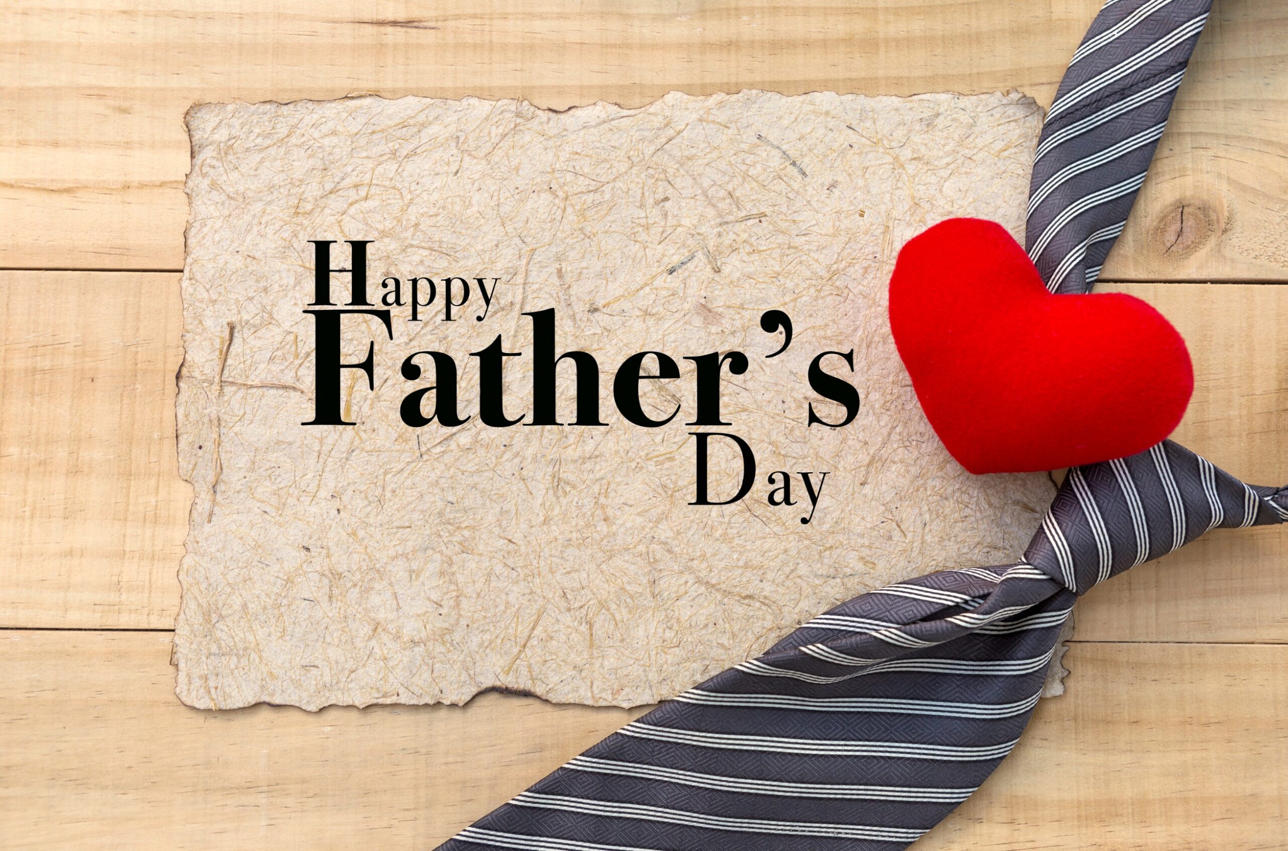 Text of Happy Fathe'rs Day with a gray and white striped tie and a red heart